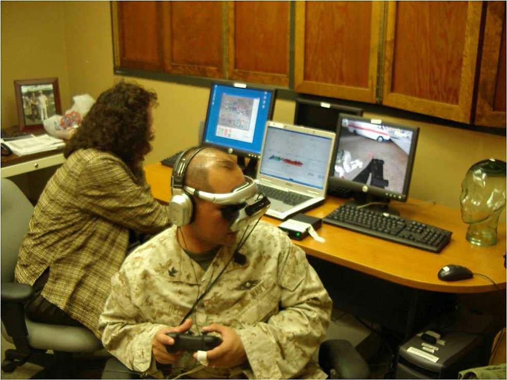 Three-computer-configurations-for-VR-GET-with-biofeedback-being-calculated-on-the-laptop-computer.-Simulated-combat-veteran/non-patient-is-holding-a-handheld-controller-to-“move”-through-the-combat-environment.-A-head-mounted-display-and-headphones-facilitate-the-immersion-in-the-VR-GET-simulated-combat-environment.